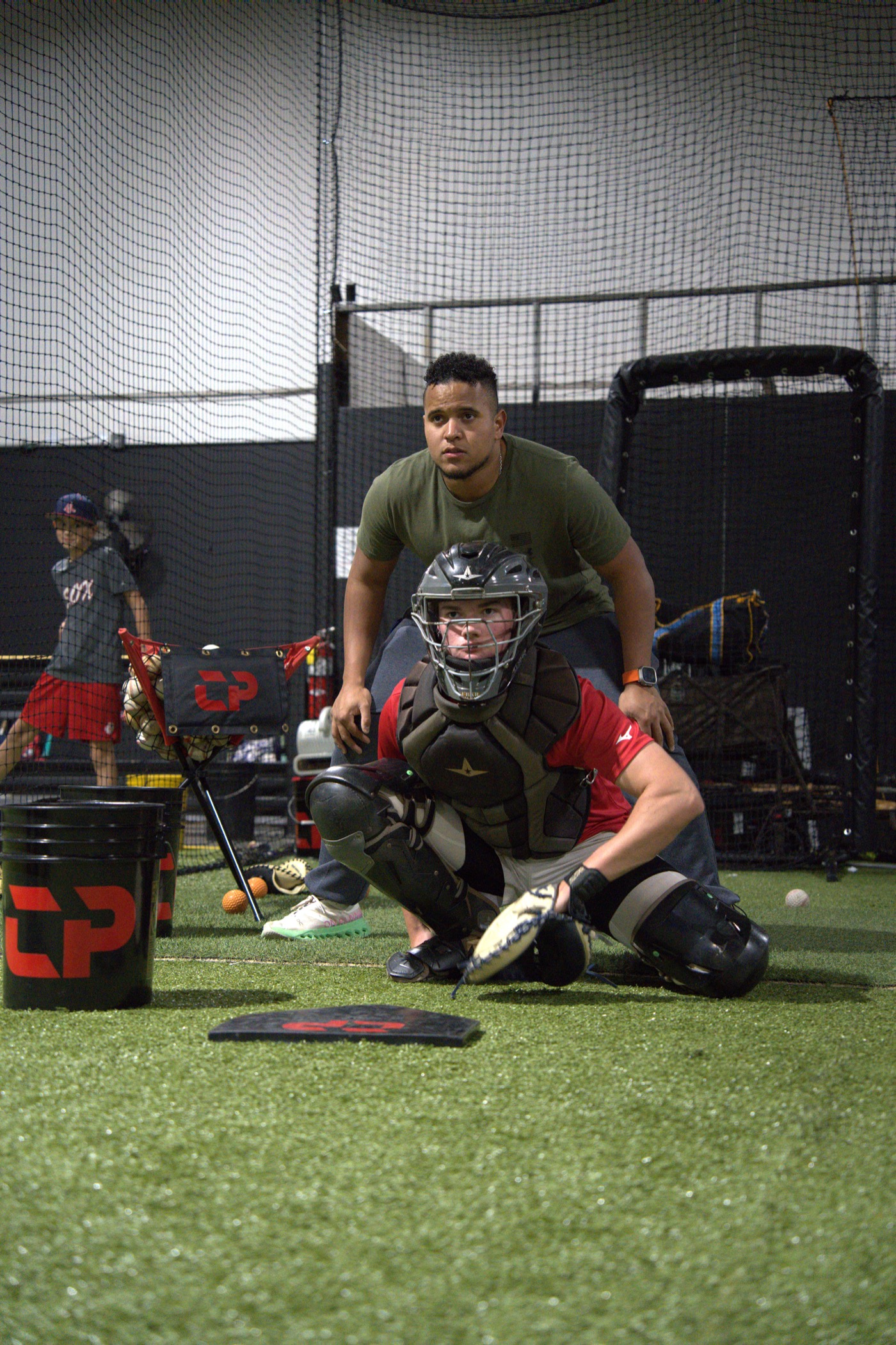 Coach Andrés guiding a catcher through positioning during a CATCHPRO ACADEMY training session