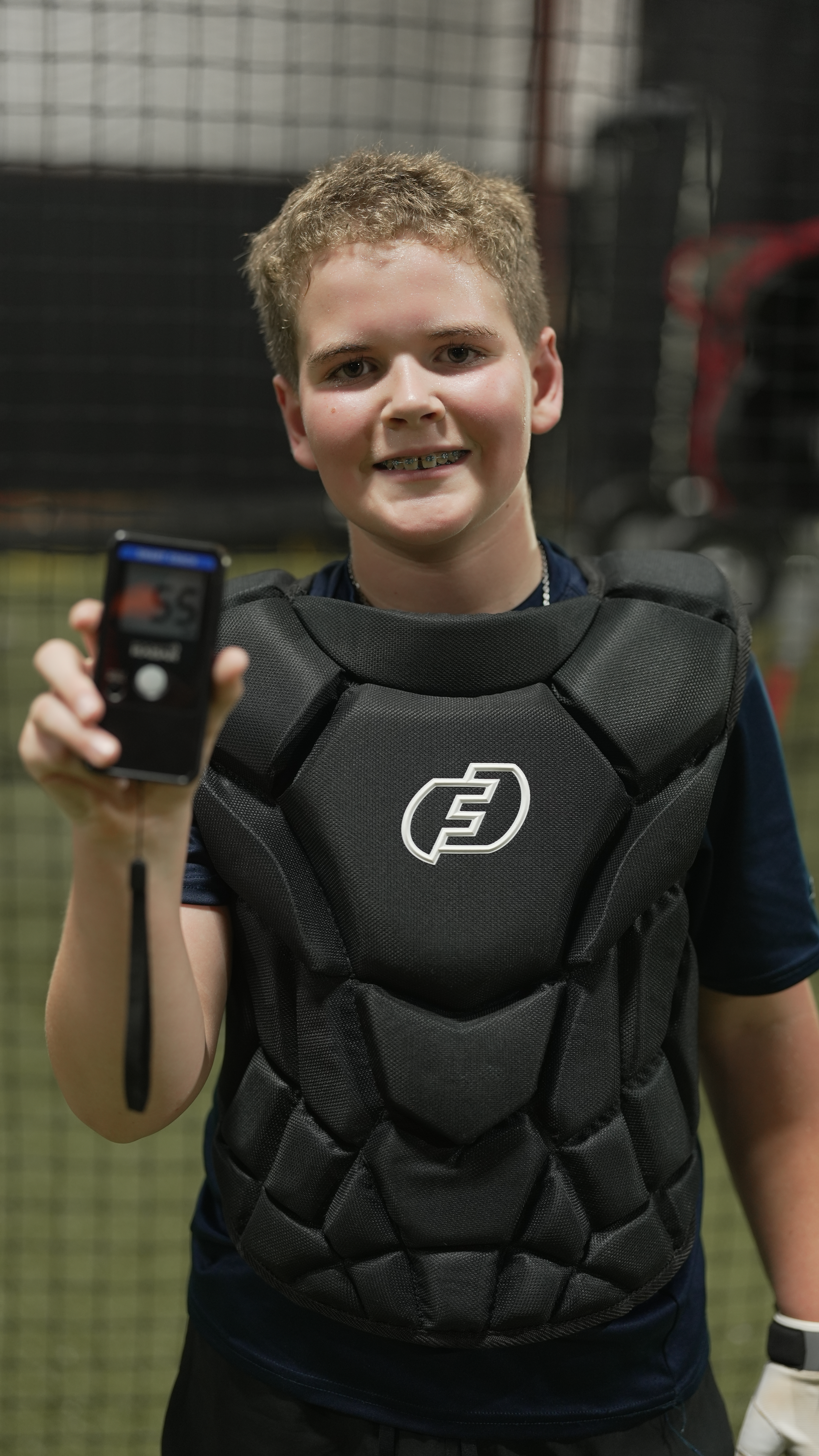 Catcher in gear holding a radar device after a training rep